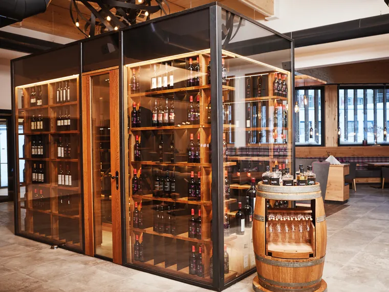 Weinregal mit Glaswänden in modernem Restaurant mit rustikalem Holzfass