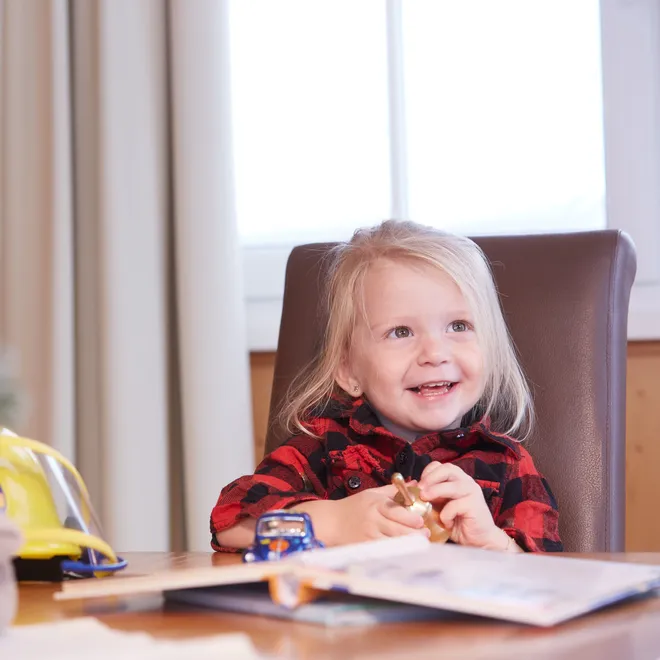 Smiling toddler at table with toys and picture book