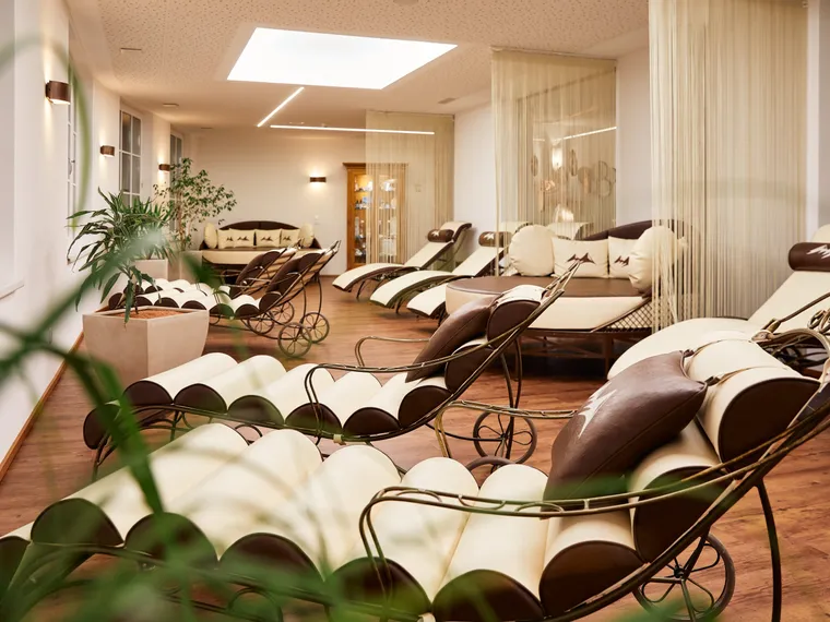 Eleganter Wellnessbereich mit komfortablen Relaxliegen und Pflanzen im warmen Licht