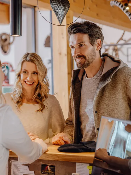 Couple smiling while checking in at hotel reception in cozy alpine lodge