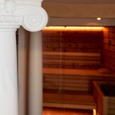 Weiße ionische Säule vor hölzerner Sauna mit warmer Beleuchtung