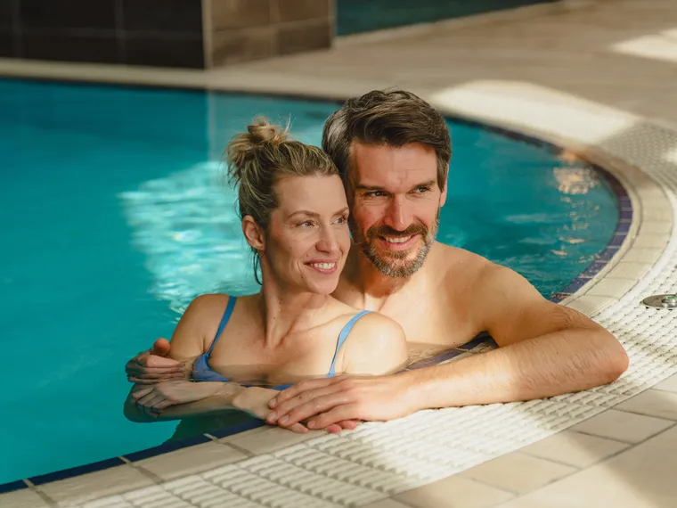 Lächelndes Paar entspannt gemeinsam im Innen-Spa-Pool