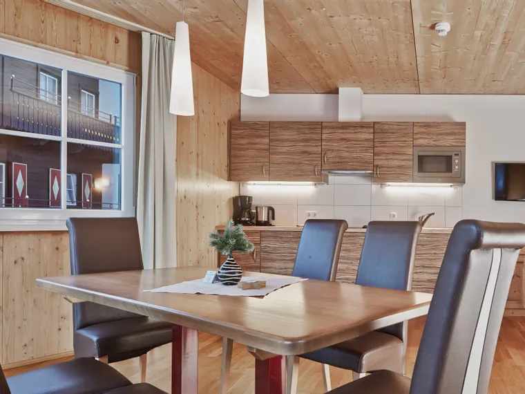 Modern holiday apartment interior with wooden decor, dining table and kitchen