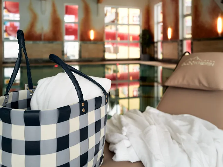 Liegestuhl mit Bademantel und Tasche am Innenpool eines Wellnesshotels