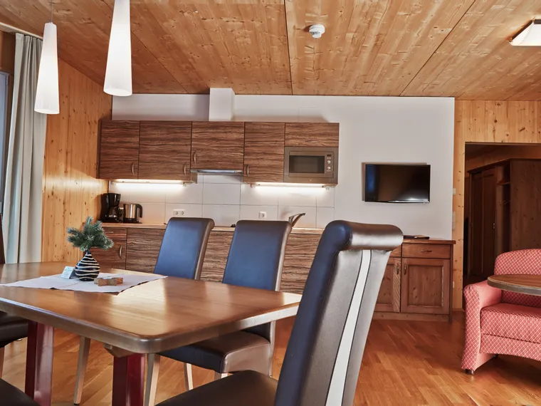 Modern alpine apartment kitchen and dining area with wood paneling and cozy furniture