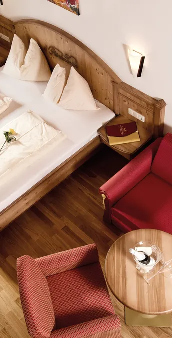 Cozy hotel room with double bed, red sofa, wooden floor and natural light