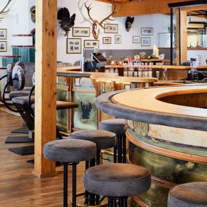 Rustikale Bar mit Holzeinrichtung, Hirschmotiven und gepolsterten Hockern