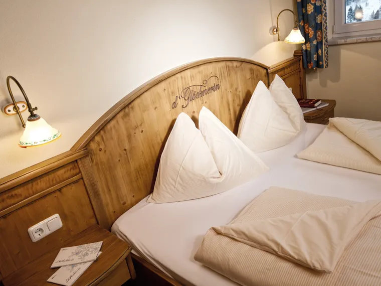 Gemütliches Hotelzimmer mit Doppelbett aus Holz und hellen Kissen