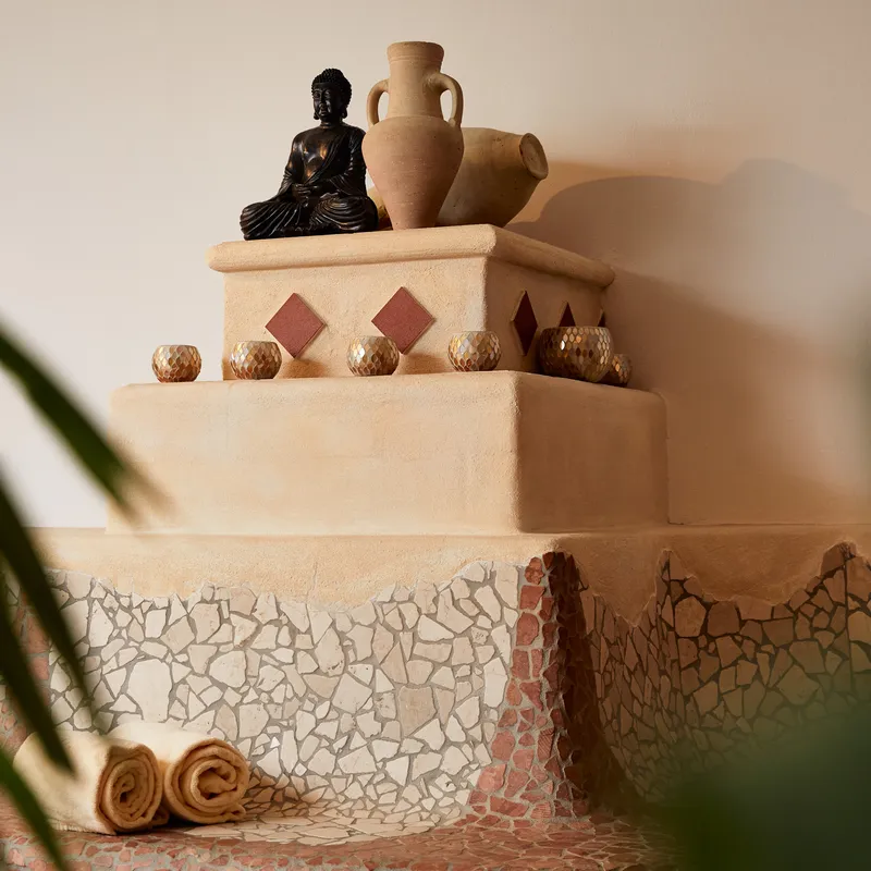 Wellnessbereich mit Buddha-Statue, Kerzen und dekorativen Amphoren