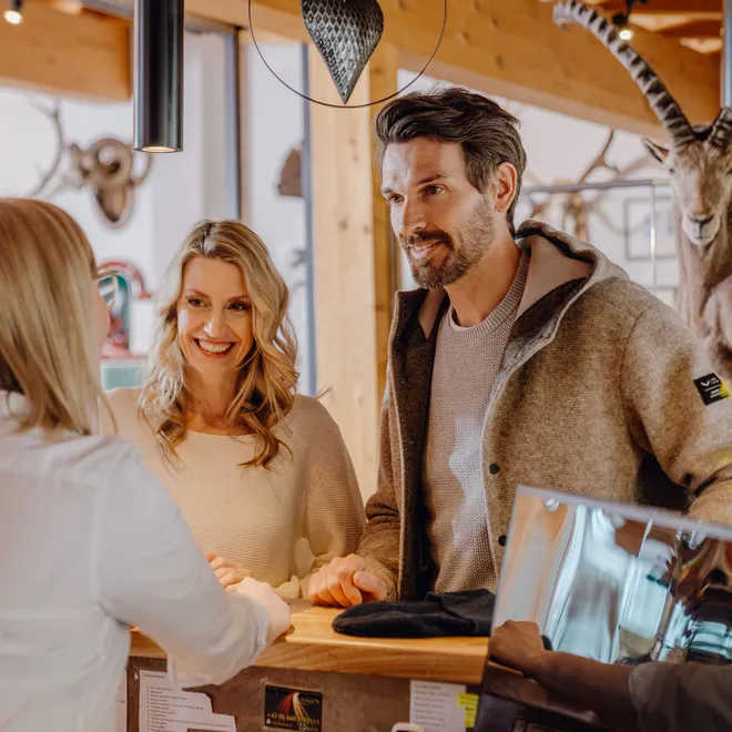 Couple smiling while checking in at hotel reception in cozy alpine lodge