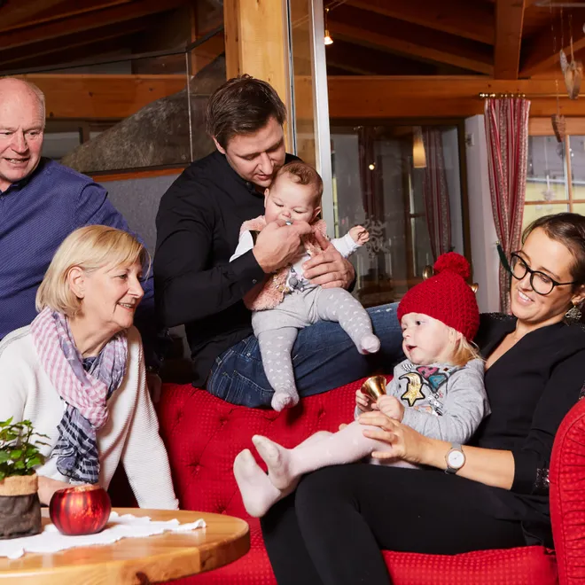 Multi-generational family sitting on red couch in cozy living room