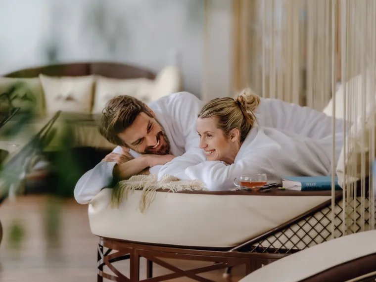 Couple in bathrobes relaxing together in a wellness lounge area
