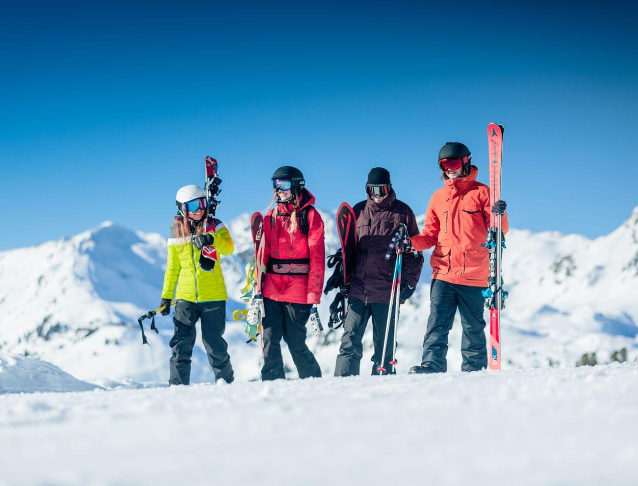 Group of skiers with gear on snowy mountain under clear blue sky
