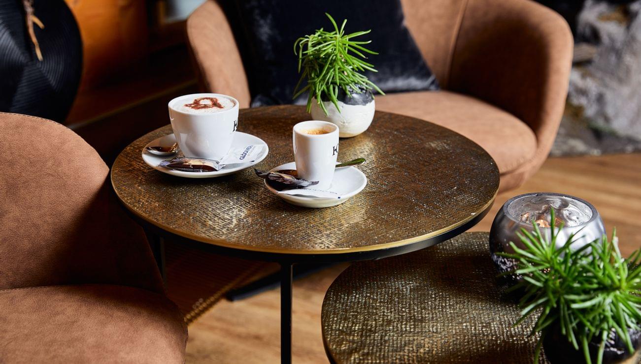 Cozy café table with cappuccino, espresso and decorative plants