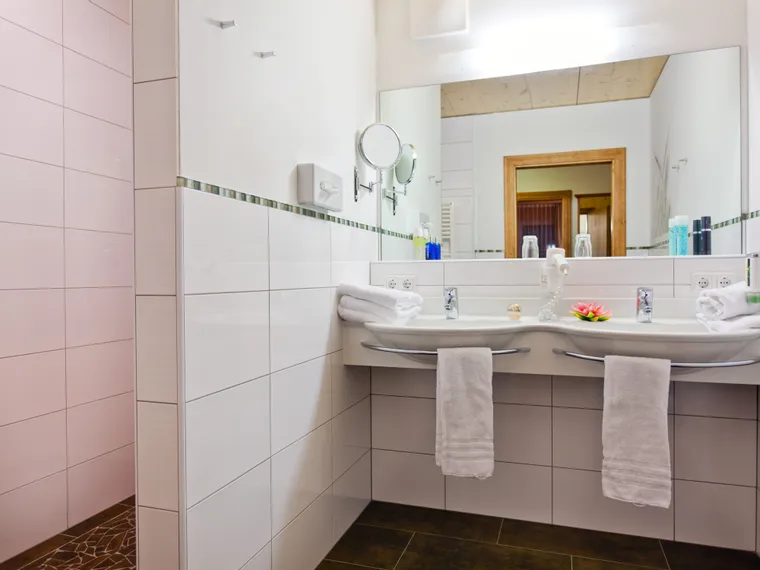 Modern bathroom with double sink, mirror, and white tiled walls