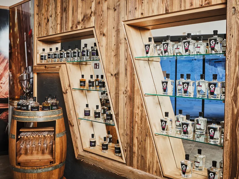 Gin bottles displayed on rustic wooden shelves and barrel in a liquor store