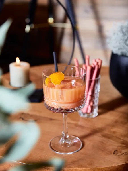 Creamy orange cocktail with orange peel garnish on wooden table