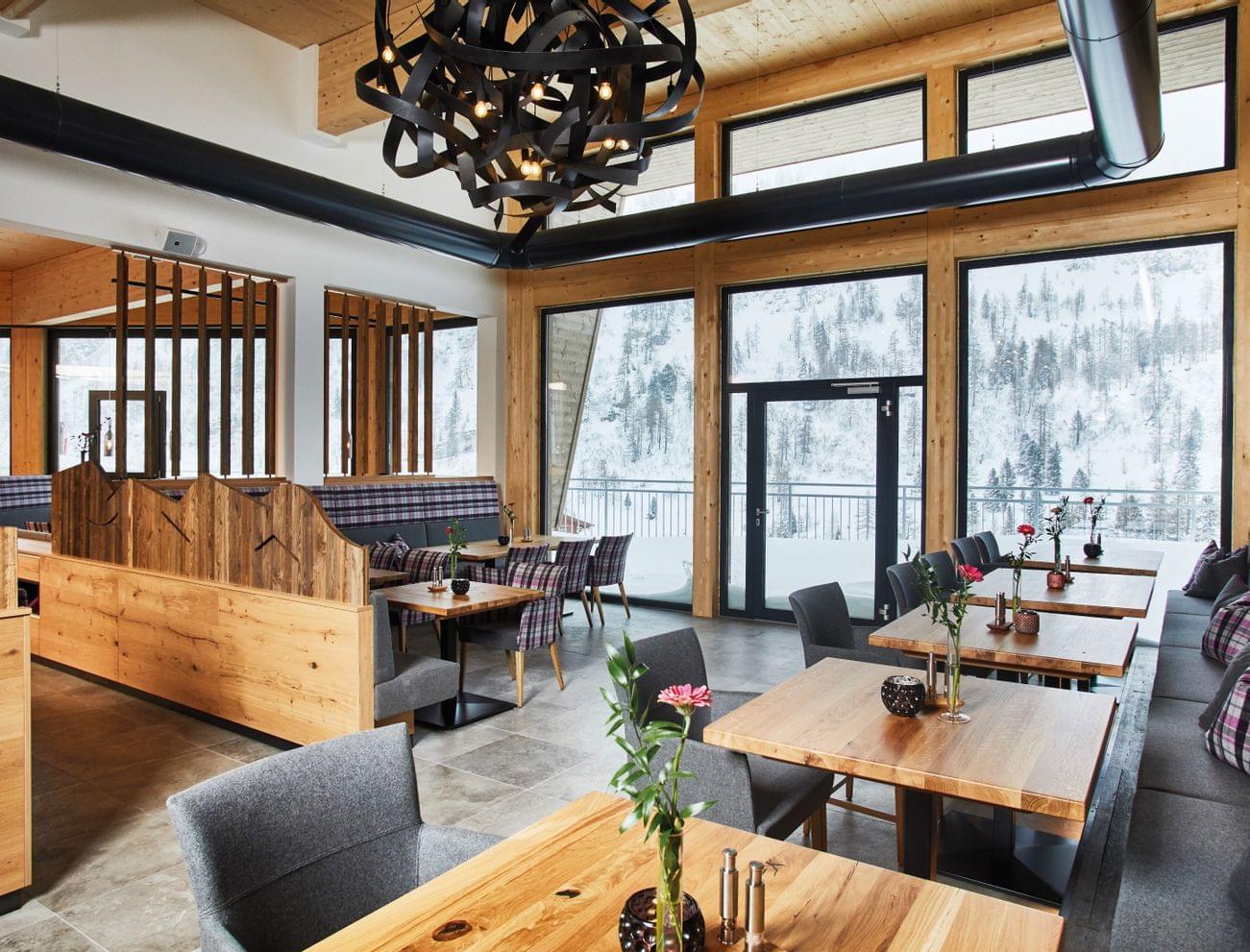 Modern restaurant interior with wooden furniture and snowy mountain view