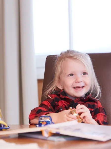 Smiling toddler at table with toys and picture book