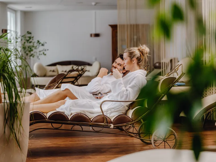 Couple in bathrobes relaxing in spa lounge while enjoying drinks