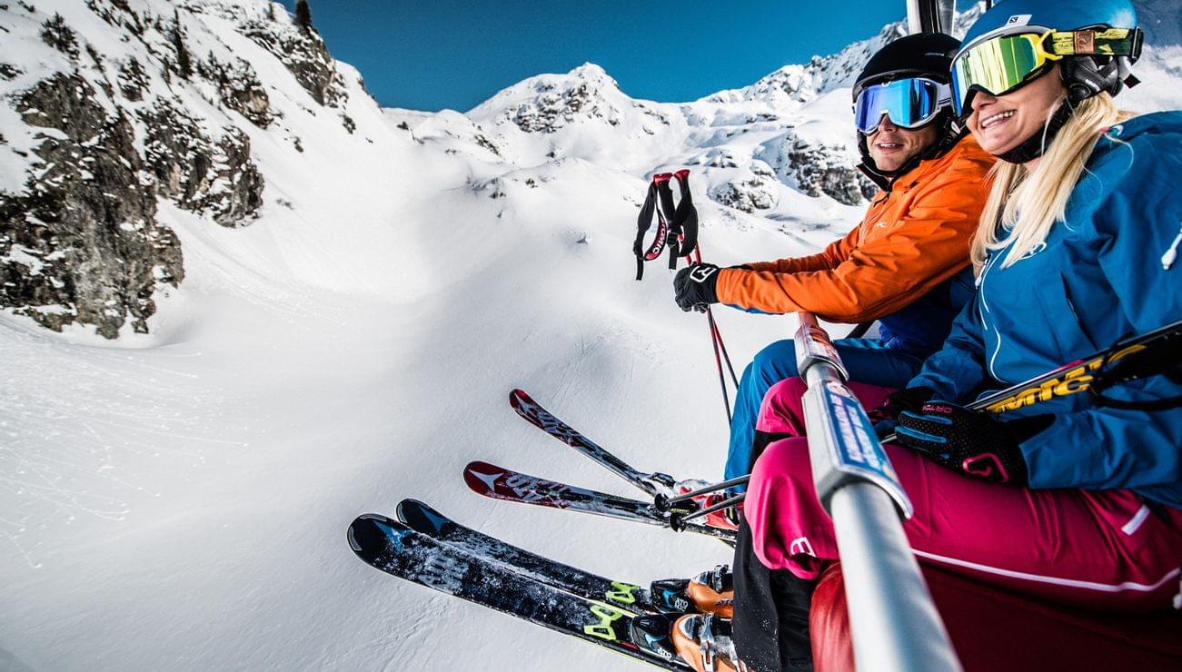 Paar mit Skiausrüstung auf Sessellift in verschneiten Alpen