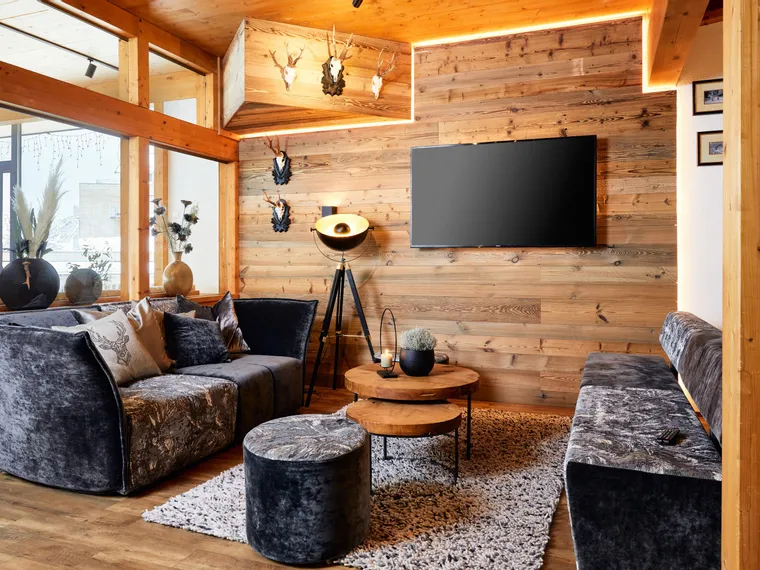 Gemütliches Alpen-Wohnzimmer mit Holzverkleidung, Samtsofas und moderner Dekoration