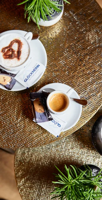 Cappuccino with heart latte art and espresso served with cookies on stylish café table