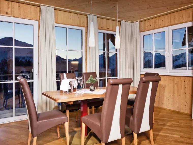 Modern dining area with wood paneling and mountain view through large windows