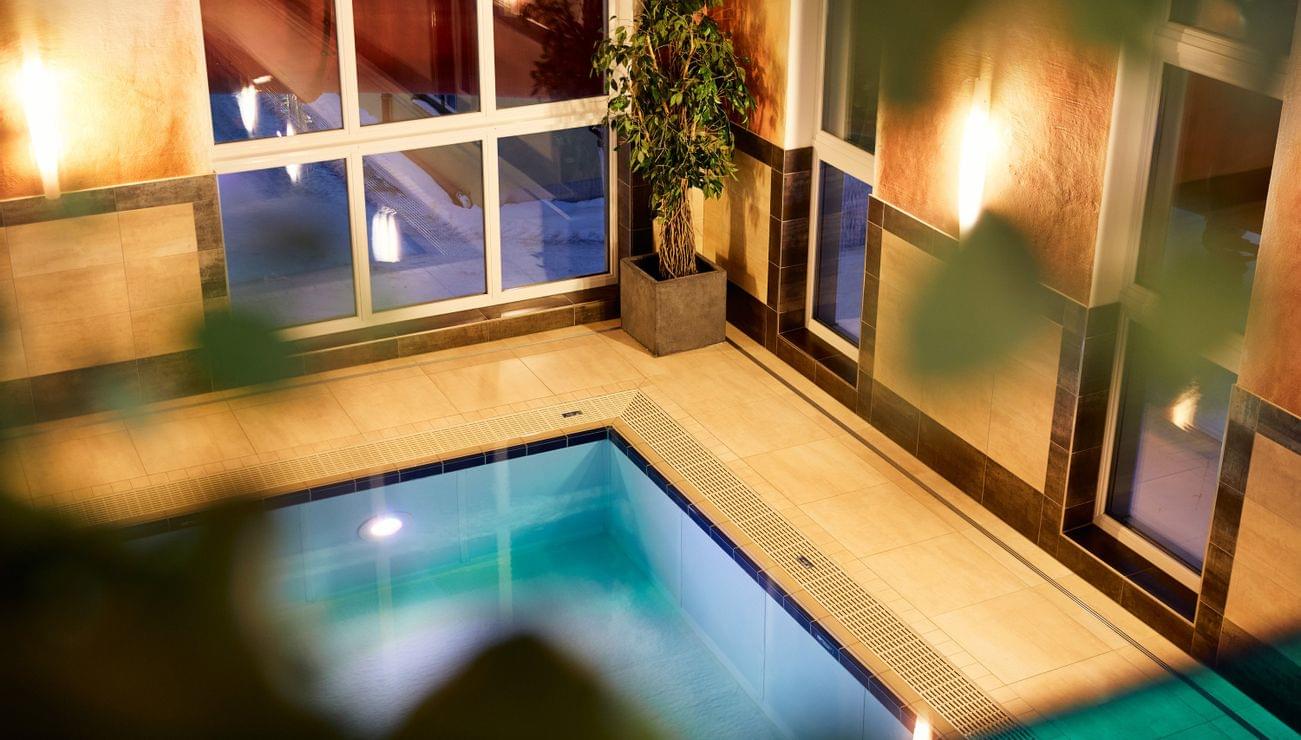 Hotel-Innenpool mit Fliesenboden und warmer Ambientebeleuchtung