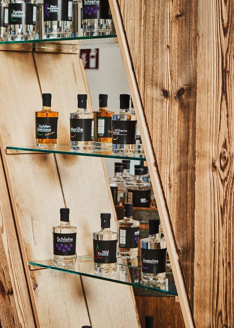 Selection of fruit brandies in glass bottles displayed on wooden shelves