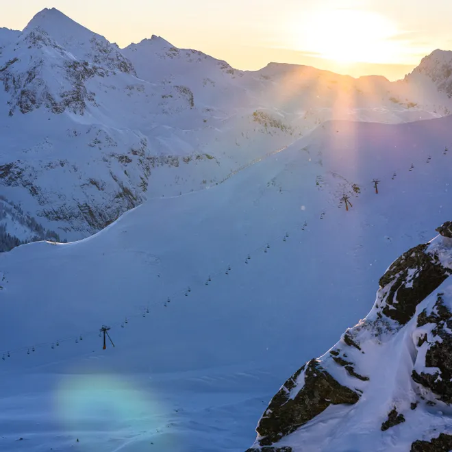 Snowy mountain landscape with ski lifts at sunrise in winter