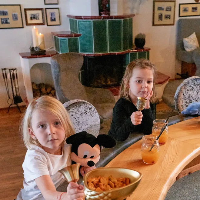 Zwei Kinder mit Getränken und Snacks an einer Bar in rustikalem Wohnzimmer