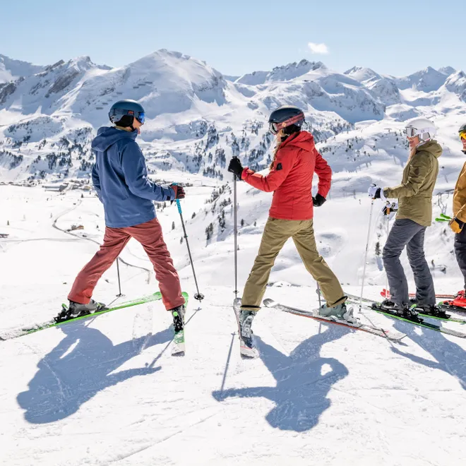 Group of skiers on snowy mountain slope with panoramic alpine view