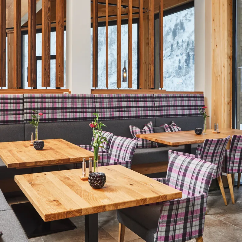 Modernes Restaurant mit Karomuster-Polstern und Blick auf verschneite Berge