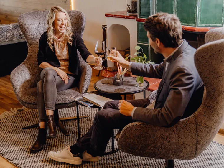 Happy couple toasting with wine in cozy lounge with stylish decor