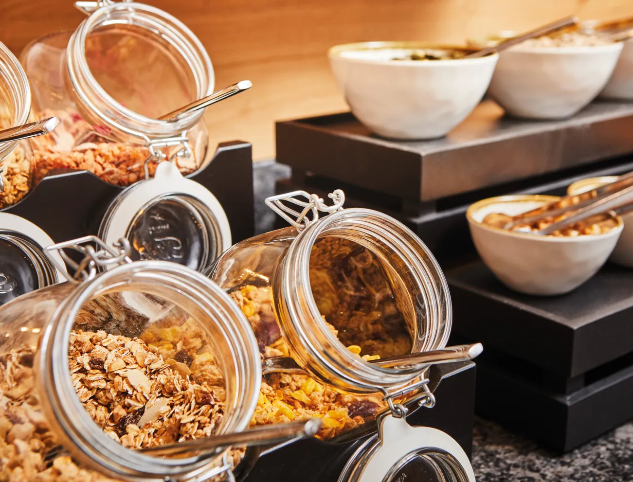 Verschiedene Müslis und Cerealien in Glasbehältern und Schalen am Frühstücksbuffet