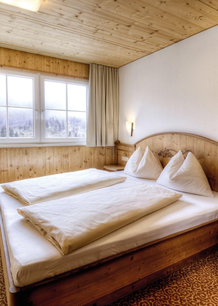 Gemütliches Alpenhotelzimmer mit Holzmöbeln, Doppelbett und Bergblick