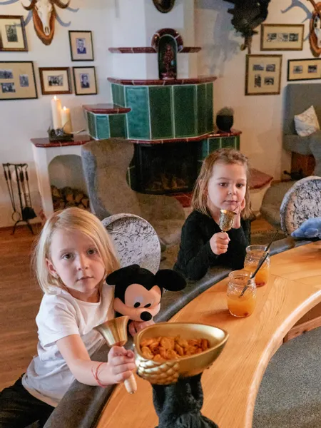 Two kids with drinks and snacks at a bar in a rustic living room