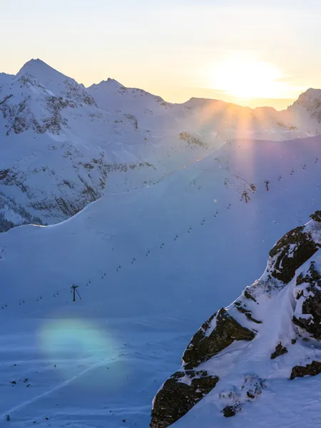 Snowy mountain landscape with ski lifts at sunrise in winter