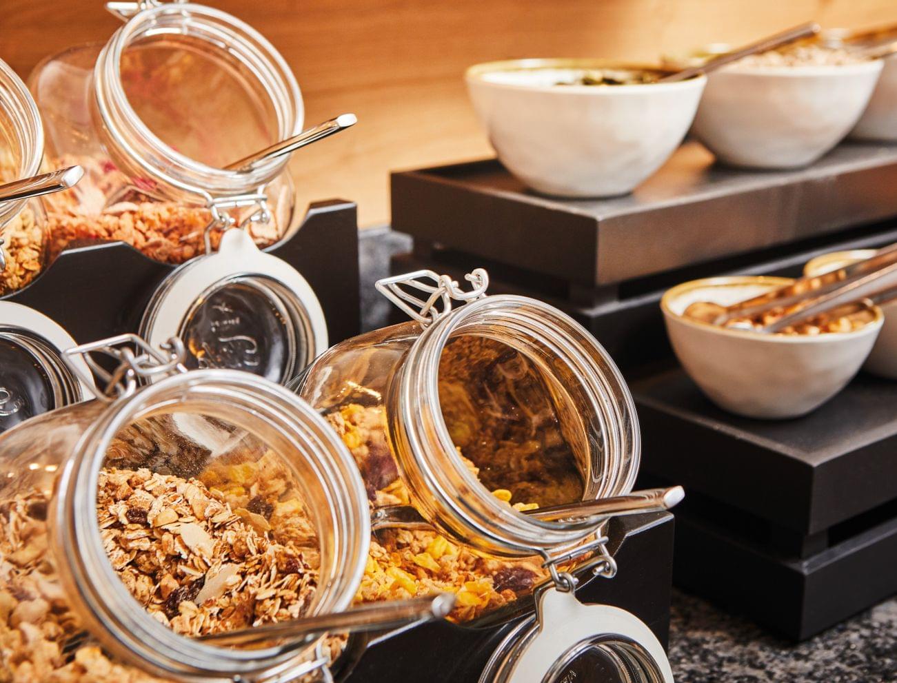 Verschiedene Müslis und Cerealien in Glasbehältern und Schalen am Frühstücksbuffet