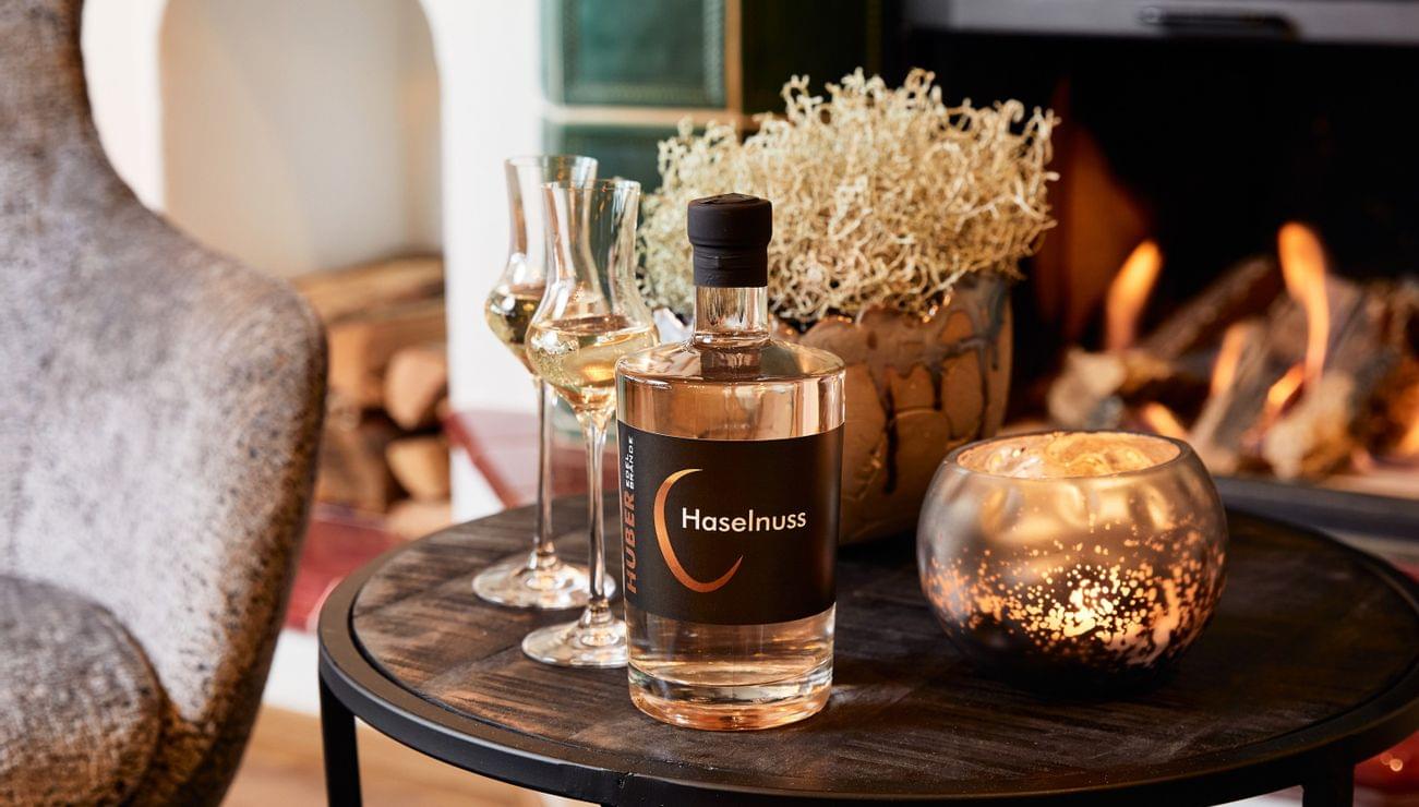 Hazelnut liqueur bottle with glasses on a table by the fireplace