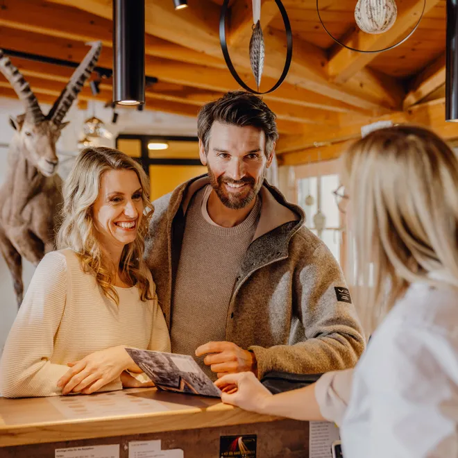 Smiling couple at hotel reception desk talking with receptionist