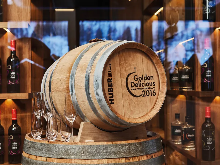 Golden Delicious 2016 oak barrel with glasses in front of liquor bottle shelves