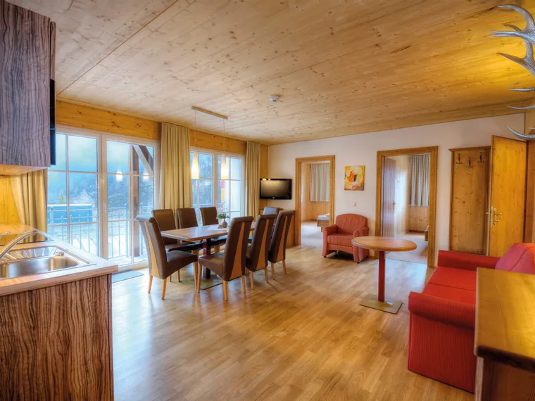 Cozy alpine holiday apartment with wooden interior, dining area, and mountain view balcony