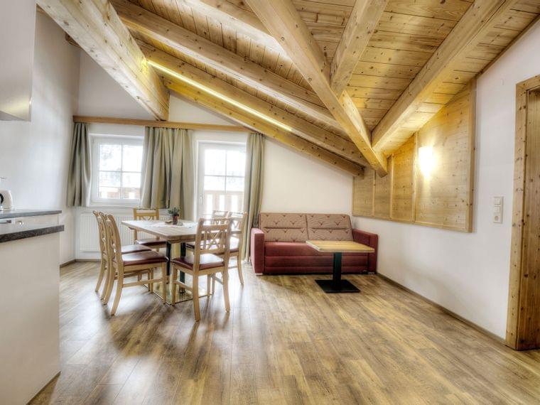 Gemütliches Apartment mit Holzbalkendecke, Essbereich und rotem Sofa