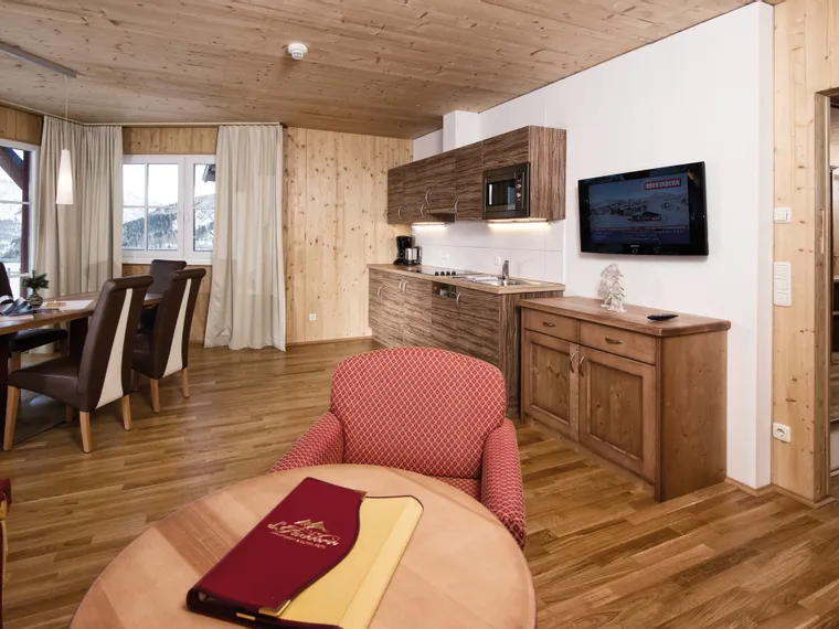 Modern alpine hotel suite with kitchenette, dining area and mountain view