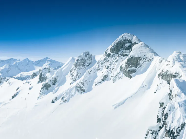 Snow-covered alpine mountains under clear blue winter sky