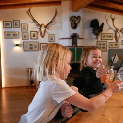 Zwei Kinder stoßen mit Getränken an einer rustikalen Bar an