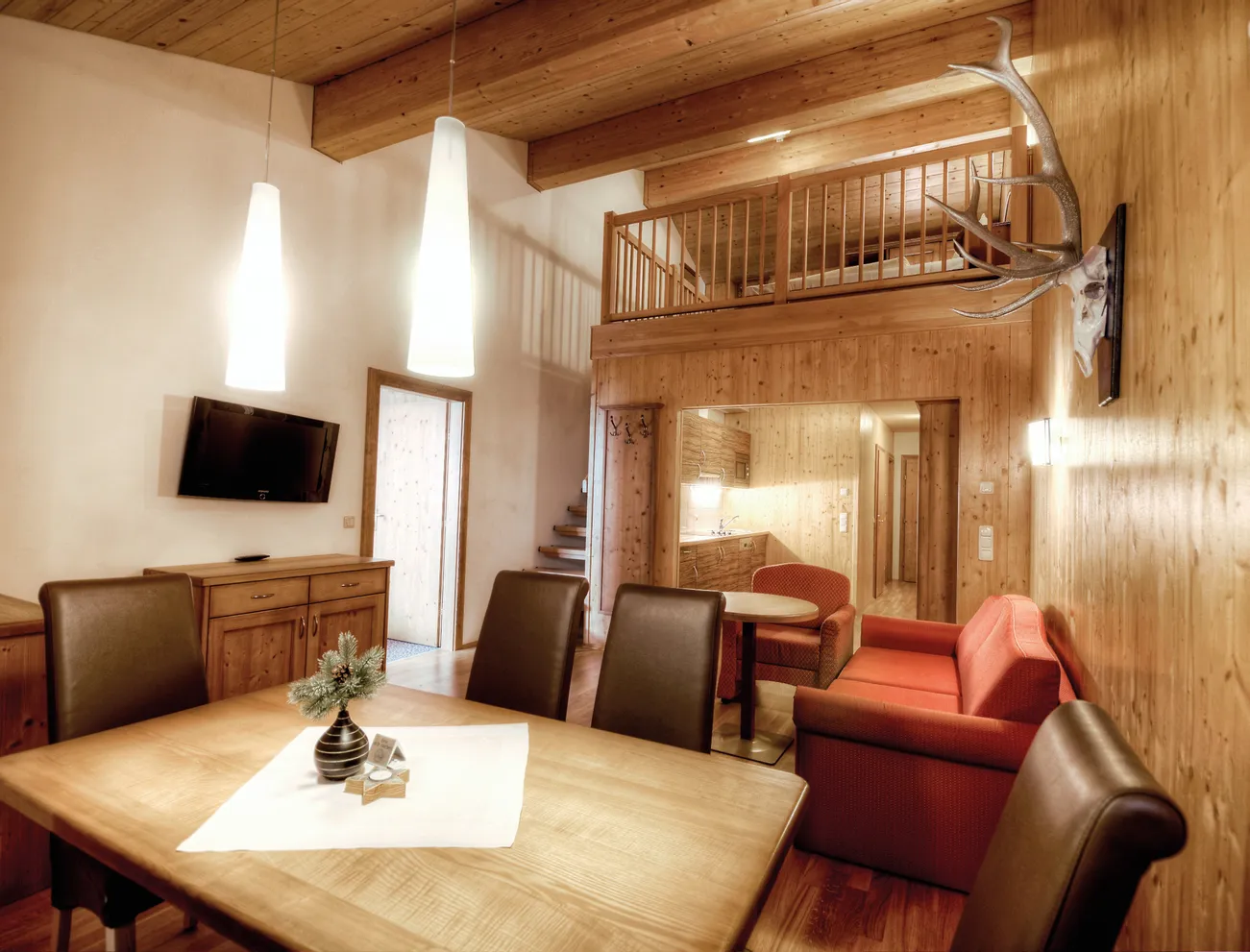 Gemütliches Chalet-Wohnzimmer mit Holzwänden, Essbereich und offener Galerie