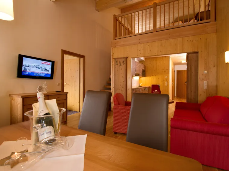 Cozy alpine-style hotel room with wood interior, seating area and mezzanine